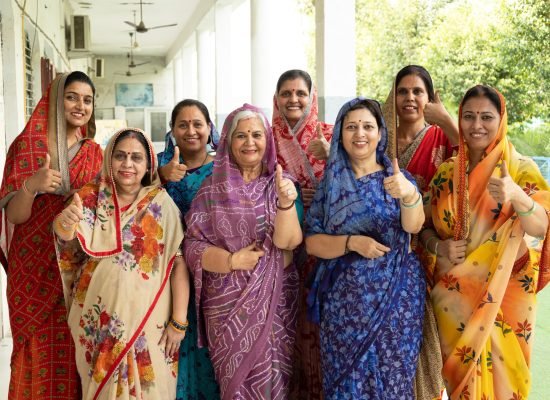 Group of rural NGO women standing together and showing thumbs up while looking at the camera. Community empowerment, women leadership, self-help group, confidence, social development, rural India.